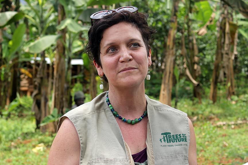 Brandy Lellou, smiling in a woodland area wearing a Trees for the Future branded top