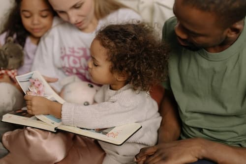 A Young Girl Holding a Photo Album while Sitting Beside Her Family