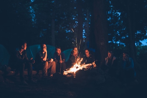 A group of friends camping and sat around a campfire