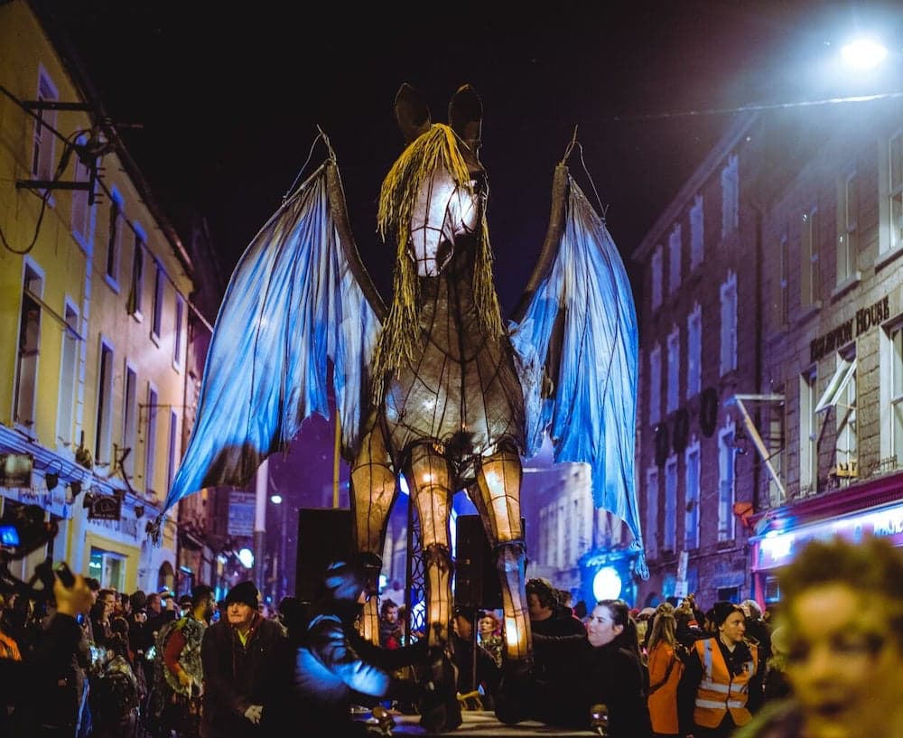 20-foot unicorn float being paraded down road at night