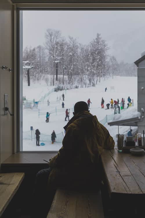 A man looking out of the window at the ski slopes