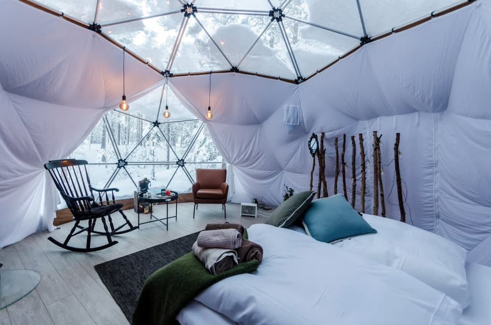 Inside of a canvas snow dome hotel room in Norway with snow outside the panes of glass