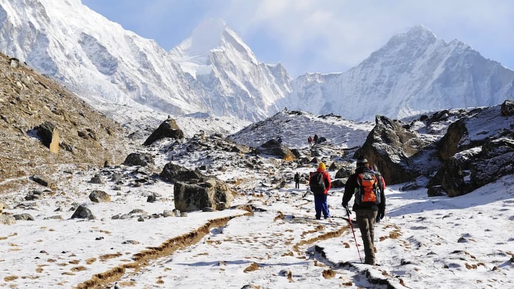 Group of people hiking up snowy mountain-face in a line