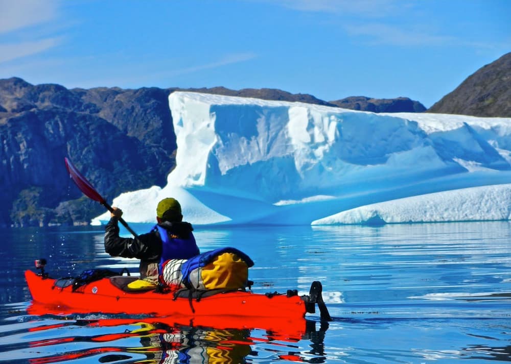 Solo-kayak in still water with ice cap in background