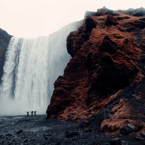 Three men standing at a waterfall