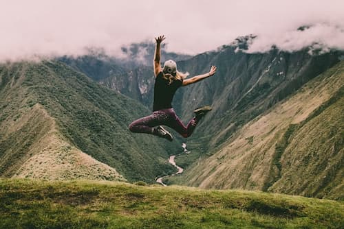 A girl jumping on top of a mountain