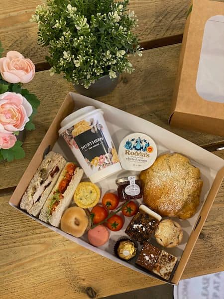 collection of afternoon tea items, including scones, sandwiches, clotted cream, and chocolates