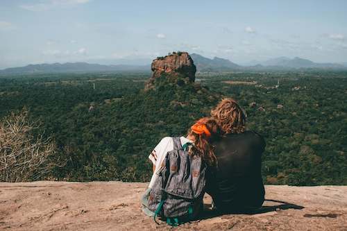 A couple sat on a mountain looking at the Lion Rock in Sri Lanka