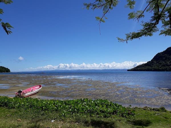 Blue skies towering above turquoise water with small beached boat nearby