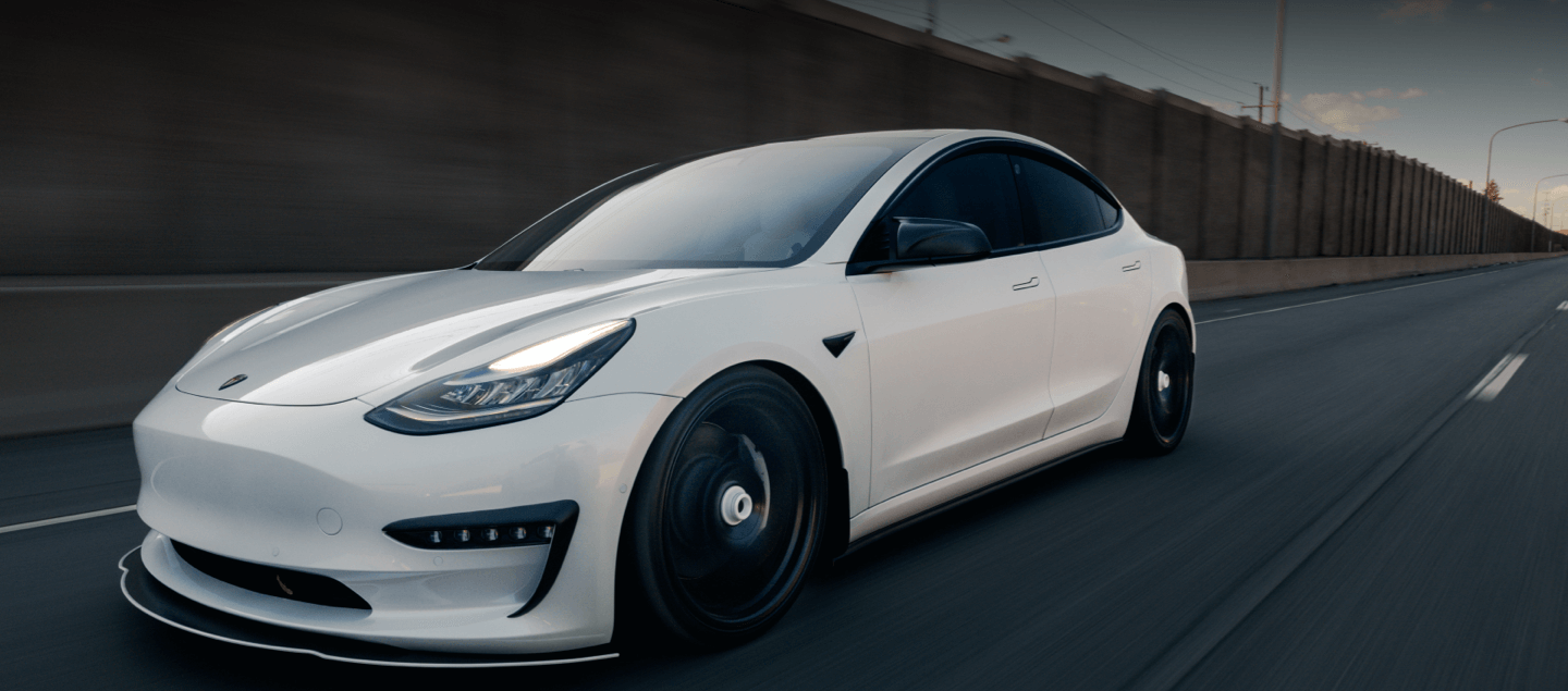action shot of white Tesla model 3 driving quickly