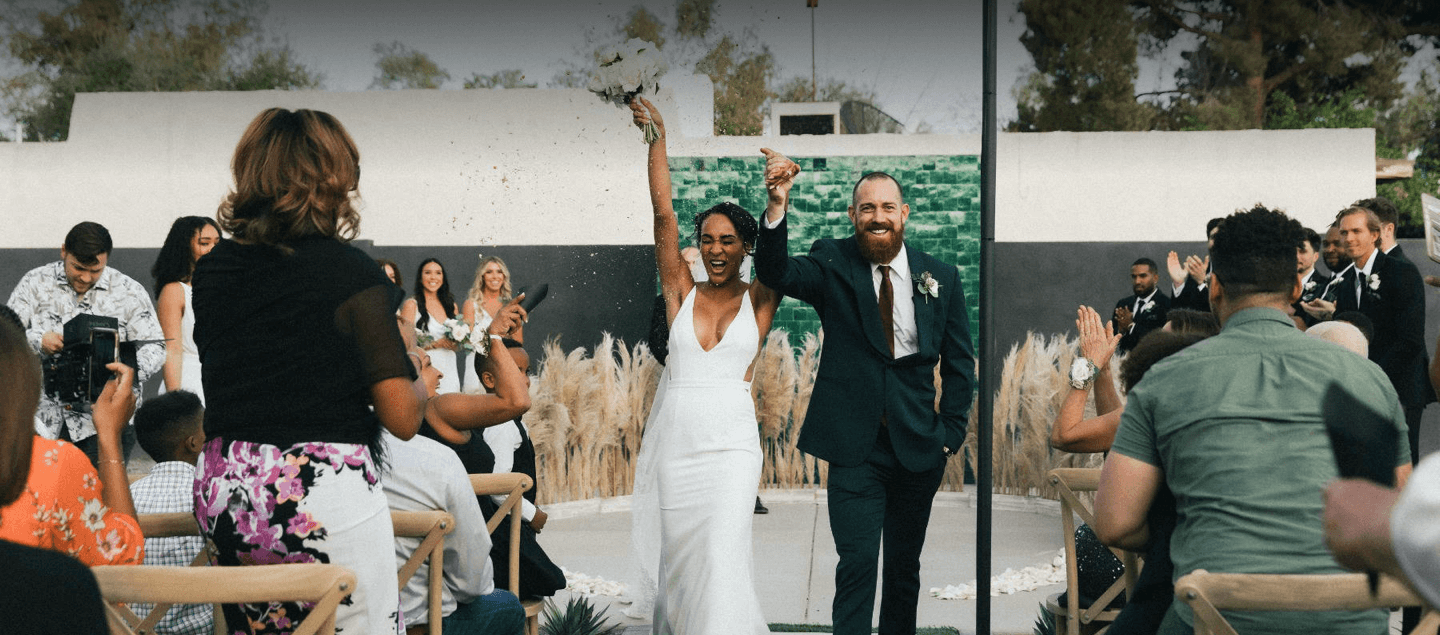 newlyweds walking down aisle while confetti is thrown above them